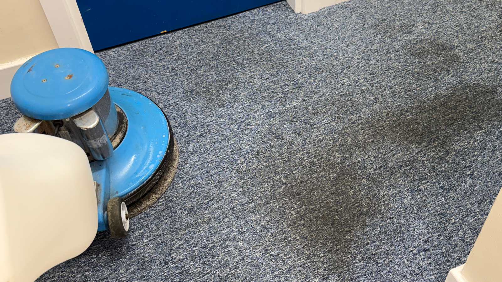 Commercial carpet with heavy traffic lane soiling and oily black staining from foot traffic