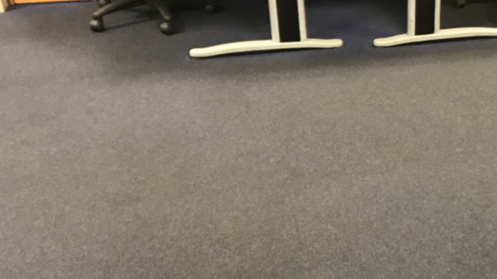 Supervisor office carpet tiles darkened by oily industrial contamination before cleaning
