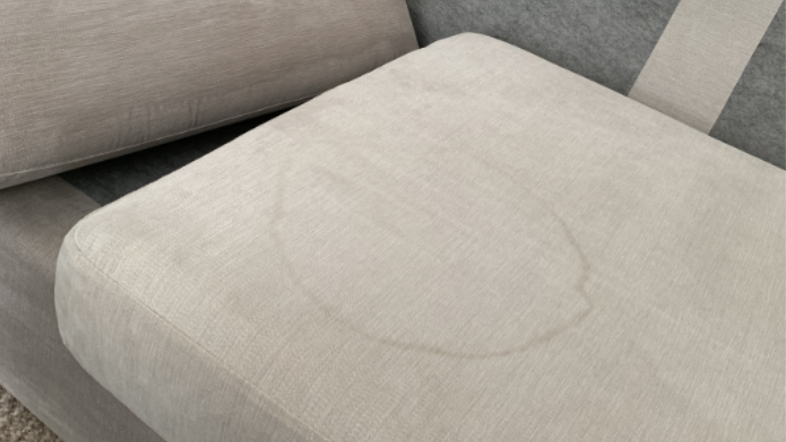 Family fabric sofa with visible water marks and staining before upholstery cleaning
