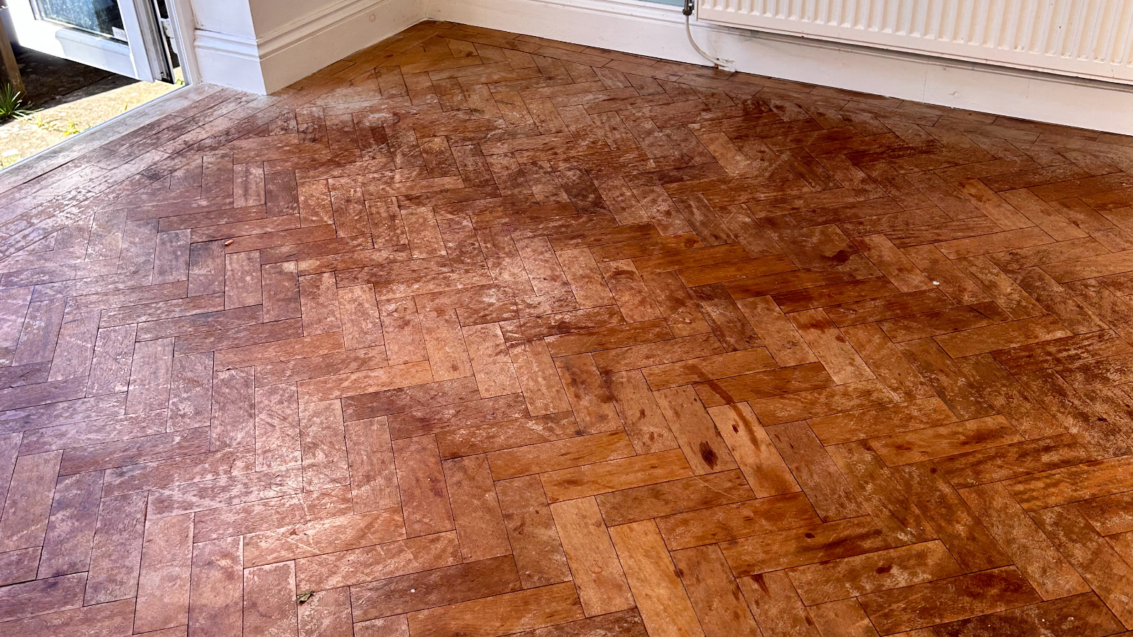 Worn parquet floor before restoration treatment