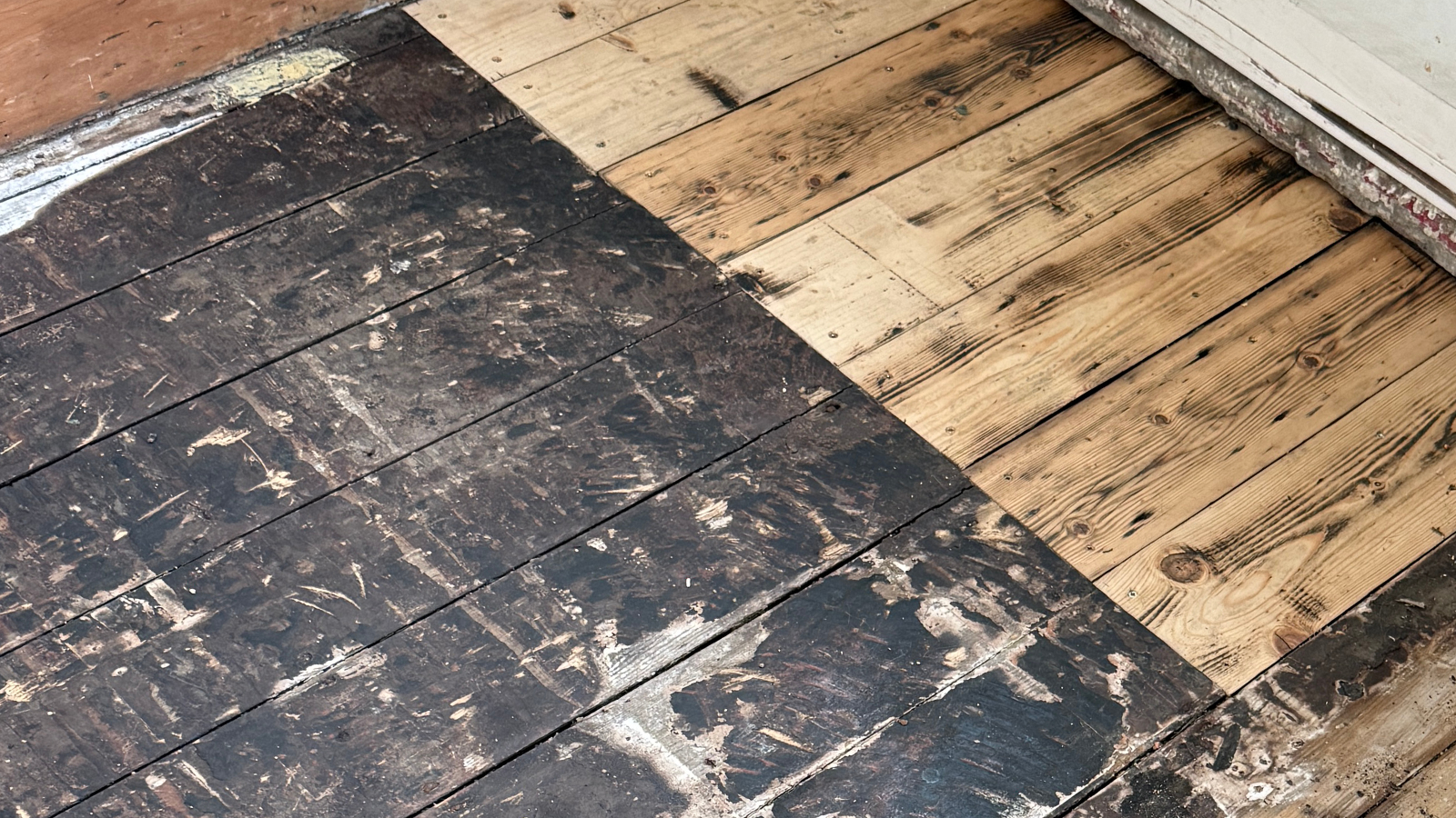 Pine floorboards covered in bitumen residue before restoration in Whickham