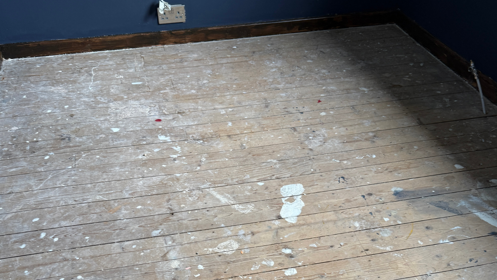 Original pine bedroom floorboards before sanding with paint marks and wear